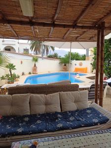 a couch under an umbrella in front of a pool at La casa de Irina in Albir