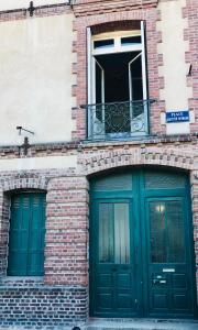 un edificio de ladrillo con puertas verdes y una ventana en L'Entre-Deux Honfleur en Honfleur
