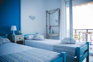 a blue bedroom with two beds and a window at Maistrali Pension in Skala Marion