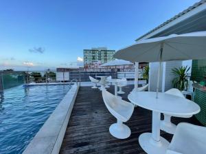 a swimming pool with tables and umbrellas on a building at Apt 219 in João Pessoa