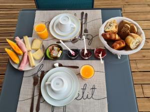 - une table de petit-déjeuner avec des aliments pour le petit-déjeuner et du jus d'orange dans l'établissement Le Petit Chêne, à Orgnac-lʼAven