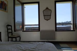 um quarto com janelas, uma cama e uma cadeira em Duplex sur la mer à Saint Jean de Luz em Ciboure