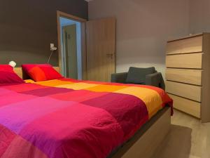 ein Schlafzimmer mit einem farbenfrohen Bett und einer Kommode in der Unterkunft Maison à deux pas du circuit in Stavelot