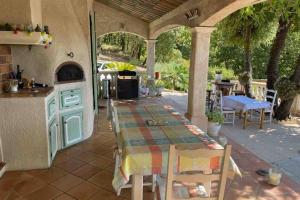 eine Terrasse mit einem Tisch und eine Küche im Freien in der Unterkunft Villa Provençale Le Mas Busien in La Motte