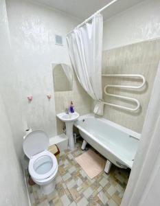 a bathroom with a toilet and a tub and a sink at Апартаменты на Ахметова 6 in Turksib