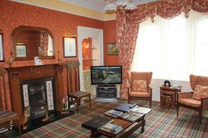 a living room with a fireplace and a tv at Glenbervie Guest House in Oban