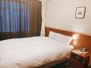 a hotel room with a white bed and a window at Dormy Inn Kanazawa Natural Hot Spring in Kanazawa