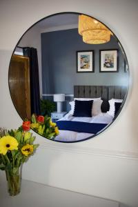 a mirror reflecting a bedroom with a bed and flowers at The Dunes in Redcar