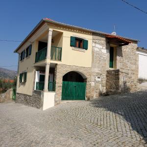 a stone house with a green door and a driveway at Casa Cabanas do Douro in Torre de Moncorvo