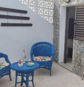 Dos sillas azules y una mesa con un plato. en Los Nudos, acogedor apartamento con patio privado., en Agaete