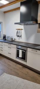 a kitchen with white cabinets and a stove top oven at Ferienwohnung Spessartbude in Schollbrunn +19 photos