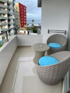 un balcón con sillas de mimbre y mesas en un edificio en Acogedor departamento junto al mar - Tonsupa en Tonsupa