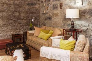 a living room with two couches and a stone wall at Moradia no Largo in Furnas