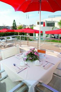 a white table with a red umbrella and flowers on it at Ganimede Hotel in Sperlonga