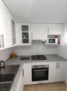 a kitchen with white cabinets and a stove top oven at Precioso apartamento en la playa de Bellreguard in Bellreguart