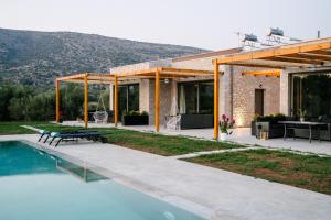 uma casa com piscina ao lado de uma casa com mesa em Irissa Suites em Paralía Iríon