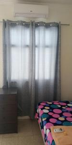 a bedroom with a bed and a window with curtains at Boel Boutique Suite en Guayaquil in Guayaquil