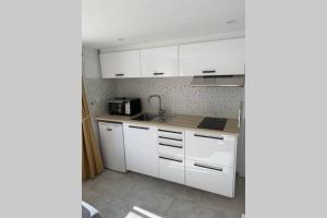 a kitchen with white cabinets and a sink at Nouveau - studio aux portes de Brest in Bohars