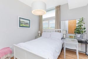 Habitación blanca con cama blanca y escritorio. en Glasgow Harbour Clyde Waterfront Apartment, en Glasgow