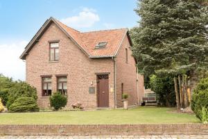 une maison en briques avec une porte marron dans une cour dans l'établissement Vakantiewoning Het Oude Laer, à Bilzen
