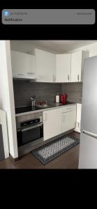 een keuken met witte kasten en een kookplaat oven bij Appartement avec piscine privée in Cagnes-sur-Mer