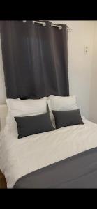 een bed met een zwart hoofdeinde en witte kussens bij Appartement avec piscine privée in Cagnes-sur-Mer
