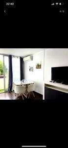 een eetkamer met een tafel, stoelen en een televisie bij Appartement avec piscine privée in Cagnes-sur-Mer