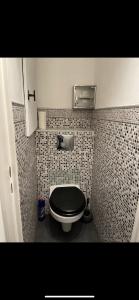 een badkamer met een toilet en een zwarte stoel bij Appartement avec piscine privée in Cagnes-sur-Mer