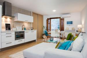 Chezmoihomes Alhambra في غرناطة: مطبخ وغرفة معيشة مع أريكة بيضاء