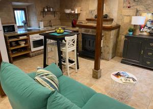 a living room with a green couch and a kitchen at El Apartamentin - en el corazón del Parque Natural de Redes in Ríoseco