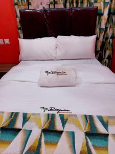 a bed with a white blanket on top of it at Eldopalm Guesthouse in Eldoret