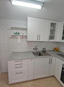 eine Küche mit weißen Schränken und einem Waschbecken in der Unterkunft Precioso apartamento en la playa de Bellreguard in Bellreguart