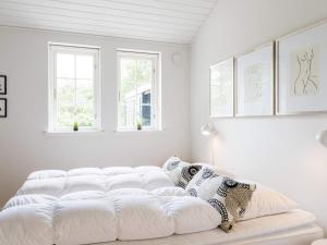 een witte slaapkamer met een groot wit bed met kussens bij Cosy Retreat in Henne Strand-By Traum in Henne Strand