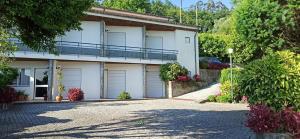 a house with garage doors and a driveway at Pensão Continental Machado in Caldelas