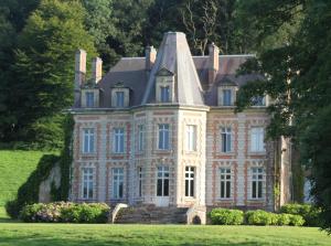 una casa vieja con una torreta en un campo de hierba en Château de la Caloterie en Montreuil-sur-Mer