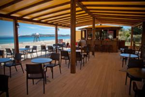 a restaurant with tables and chairs on the beach at Meltemi in Ormos Panagias