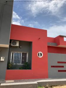 - un bâtiment rouge et blanc avec une fenêtre dans l'établissement Chez Camille a Zac Mbao, à Diokoul