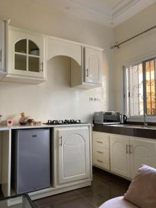 Diokoul的住宿－Chez Camille a Zac Mbao，厨房配有白色橱柜和炉灶烤箱。