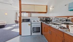 a kitchen with a white refrigerator and a sink at Motel Six in Whangarei