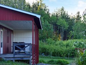 une grange rouge et blanche avec une terrasse couverte en bois dans l'établissement 4 person holiday home in ESKILSTUNA, à Eskilstuna
