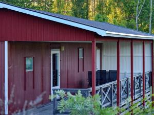 een rood huis met een veranda en een terras bij 4 person holiday home in ESKILSTUNA in Eskilstuna