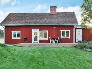 a red house with a table and chairs in front of it at 6 person holiday home in ESKILSTUNA in Eskilstuna