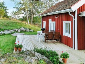 a red house with a wooden deck with a table and chairs at 6 person holiday home in ESKILSTUNA in Eskilstuna