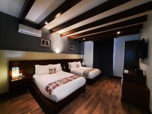 una camera d'albergo con due letti e una televisione di Casa San Miguel Hotel Boutique y Spa a Zacatlán