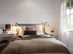 Un dormitorio con una cama grande y una ventana en Wombat Hill Cottage, en Daylesford