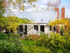 una antigua casa blanca con techo de metal en Wombat Hill Cottage, en Daylesford