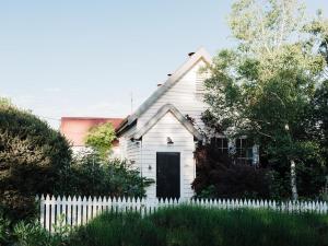 una casa blanca con una valla blanca en The Little School House, en Hepburn Springs