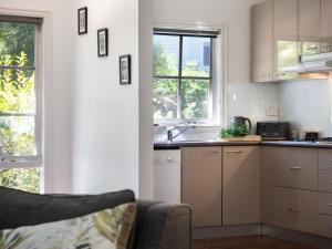 a kitchen with white cabinets and a sink and windows at Lucini Cottage in Hepburn Springs