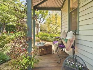 a porch of a house with a bench and a table at Quince Cottage - scenic escape with spa in Daylesford