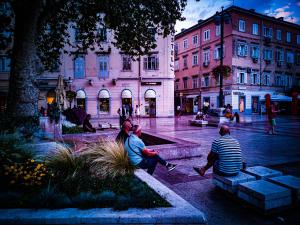 Un gruppo di persone sedute intorno a una fontana in una città di Hostel Kosy a Fiume (Rijeka)
